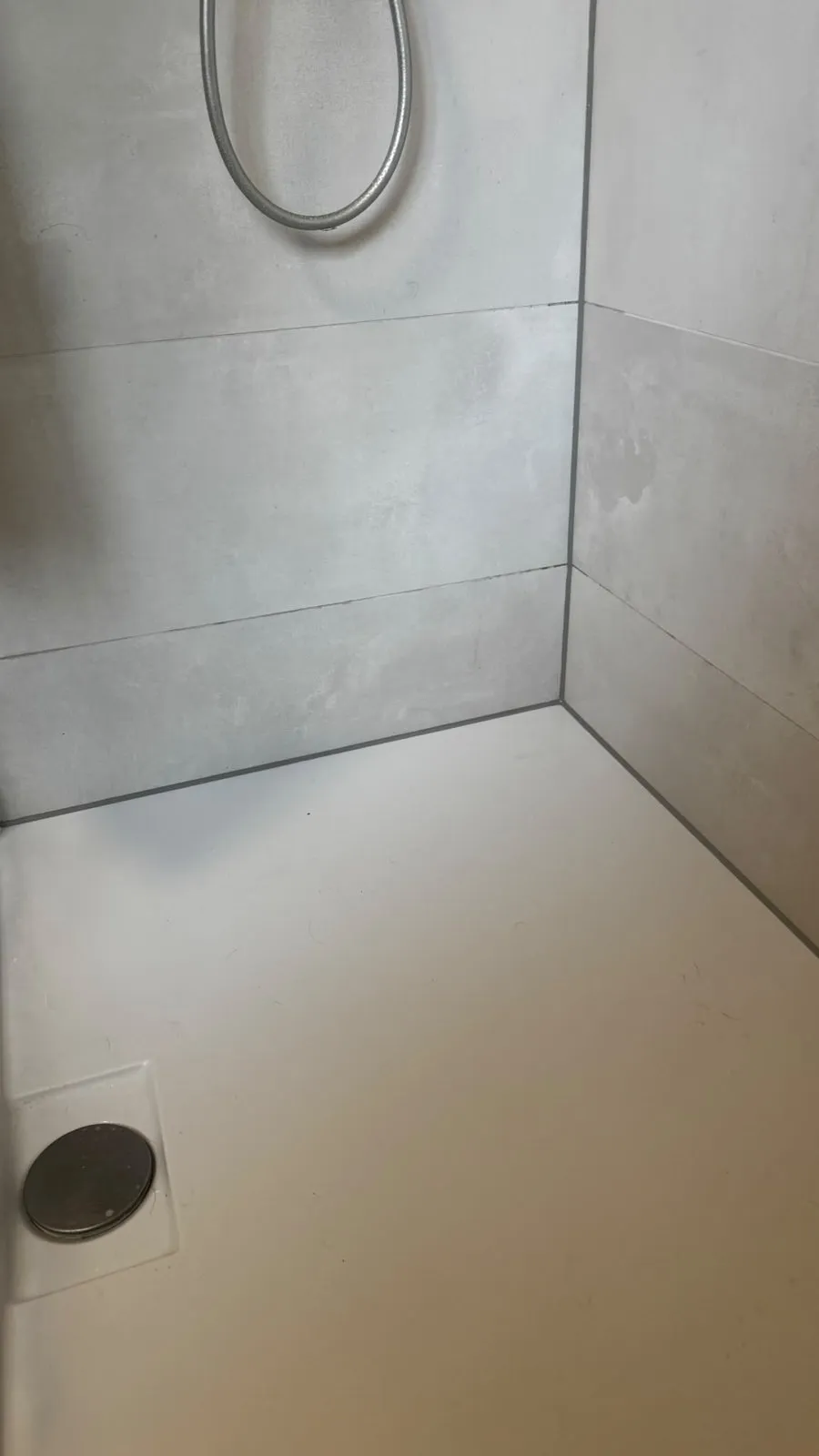 Neue Silikonfuge zur Wand in einer Dusche mit Fliesen in Betonoptik
